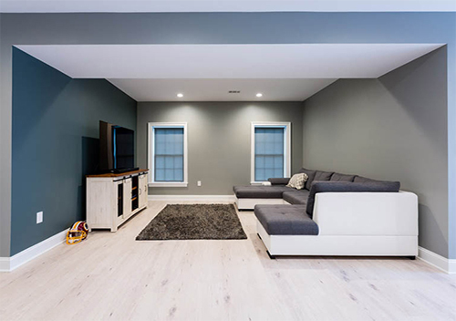 Renovated downstairs with large couch, rug, and entertainment center with TV, an example of our basement remodeling near Alexandria, Virginia.