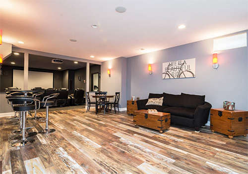 Remodeled basement with wood flooring, stools, and a screening room, done by our Countryside, Sterling full house renovation contractors.