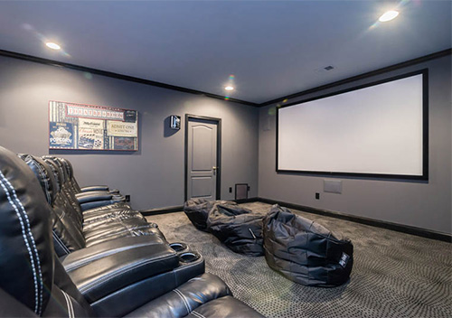 Remodeled basement with leather seats and a projection screen, an example of our Chantilly interior renovation services.