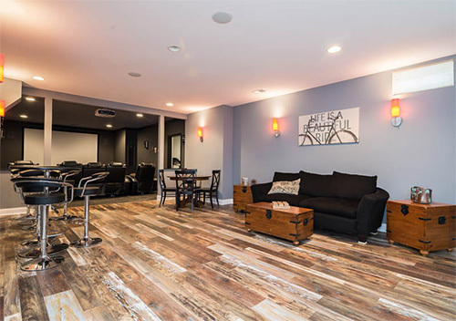 Basement with wood flooring, couch, and screening room set up by our Aldie top remodeling company.