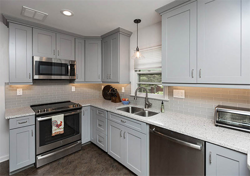 Renovated kitchen with white/grey cabinets and stainless steel appliances set up by our top Fairfax remodeler.