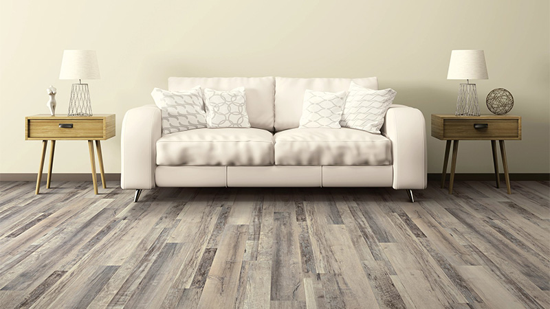 A white couch in between two wooden side tables on top of Gainesville LVP flooring.